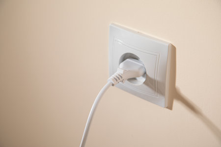 Electrical plug in the electric socket on a wall.