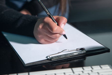 Caucasian woman writes in clipboard at home.の写真素材