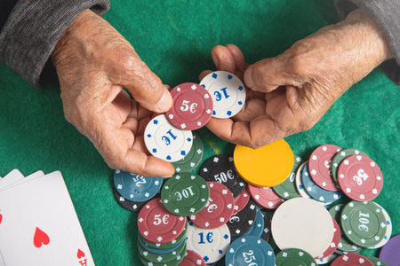 Elderly female hand holding casino games chips.