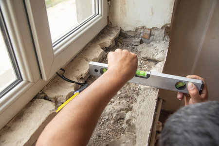 Worker measuring old window sill before renovation at home.の写真素材