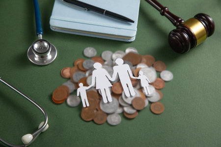 Paper family with a coins, gavel, stethoscope on the green background.