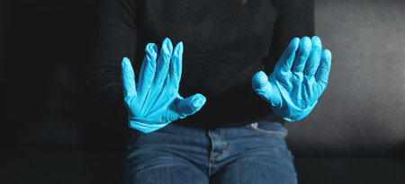 Caucasian woman wearing blue medical gloves.