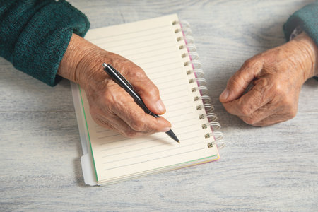 Caucasian elderly woman writes in notepad.の写真素材