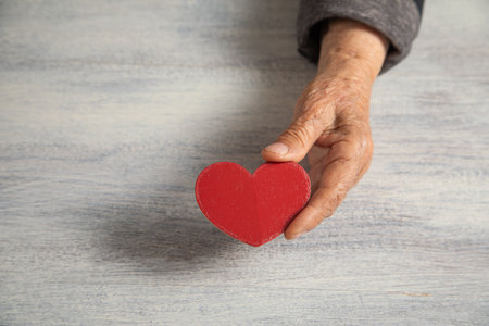 Caucasian elderly woman showing red heart.の写真素材