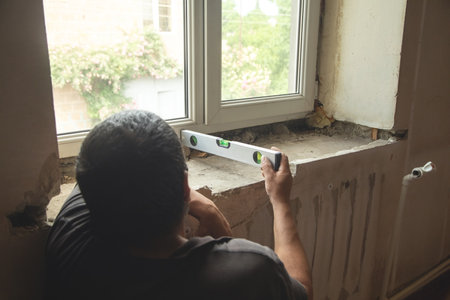 Worker measuring old window sill before renovation at home.の写真素材