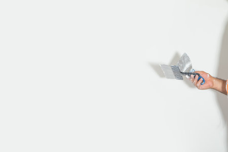 Worker hand showing spatula on wall background.の写真素材