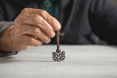 Caucasian elderly female hand with an old key.の写真素材