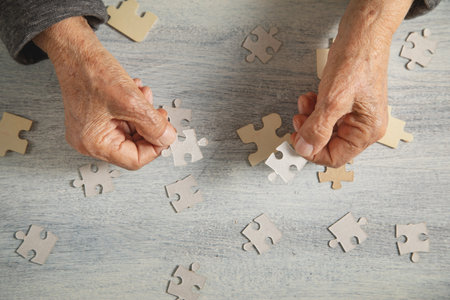 Old female hands with a jigsaw puzzle.の写真素材
