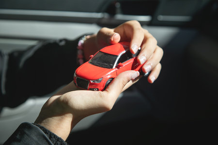 Caucasian female hand showing red toy car.の写真素材