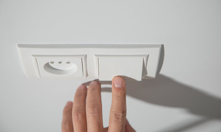 Male finger pushing light switch turn on or off.
