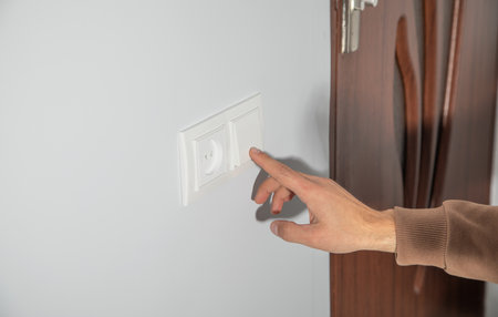 Male finger pushing light switch turn on or off.