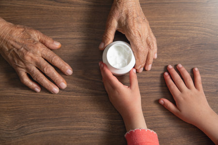 Cosmetic cream with an elderly female and young girl hands.の写真素材
