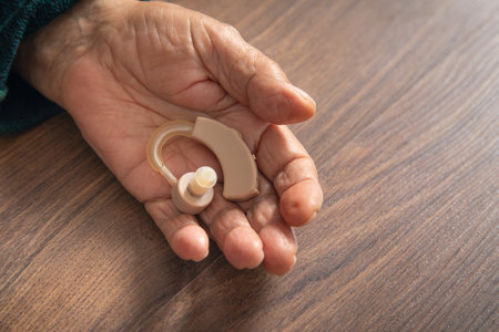 Caucasian elderly woman holding hearing aid.の写真素材