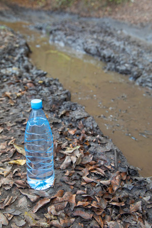 Bottle of water with a dirty road water.の写真素材