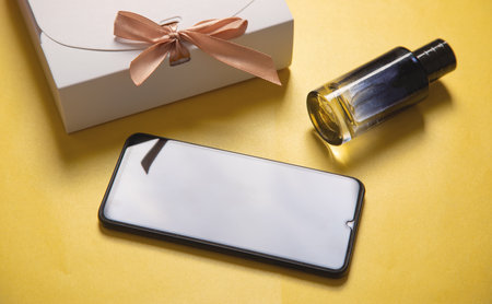 Gift box with a smartphone on the yellow background.の写真素材