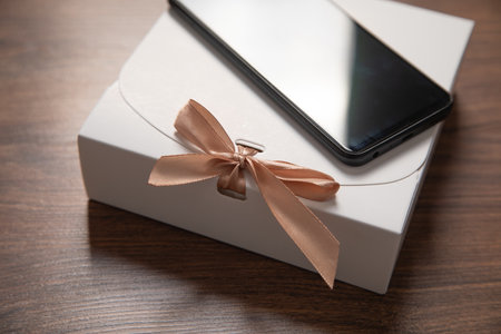 Gift box with a smartphone on the wooden background.の写真素材