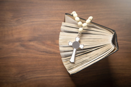 Holy Bible and rosary beads on the wooden background.の写真素材