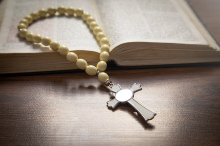 Holy Bible and rosary beads on the wooden background.