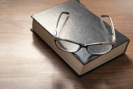 Eyeglasses and book on the wooden table.の写真素材
