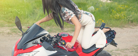 Caucasian young girl in a motorcycle at the nature.の写真素材
