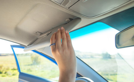 Female hand adjusting sun visor in a car.の写真素材