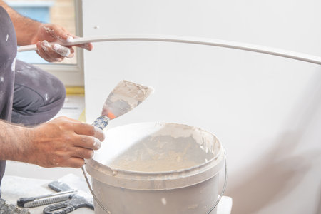 Worker applying putty on material. Renovating homeの写真素材