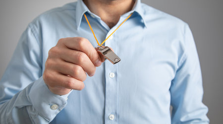 Referee or trainer holding a metal whistle.の写真素材