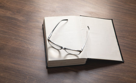 Eyeglasses and book on the wooden table.の写真素材