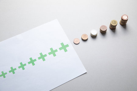 Stack of coins with a growing plus signs.の写真素材