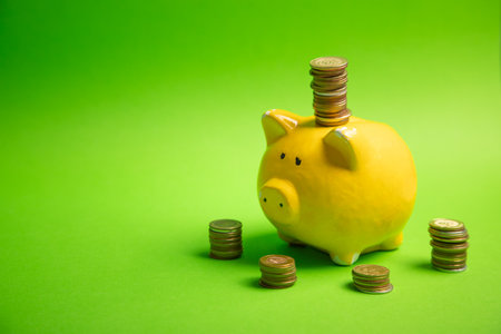 Piggy bank and coins on the green background.の写真素材
