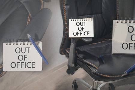 Out Of Office message on notepad with a office chair.の写真素材