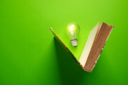 Light bulb with a book on the green background.の写真素材