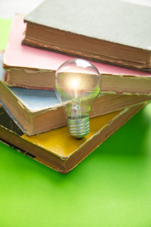 Light bulb with a book on the green background.