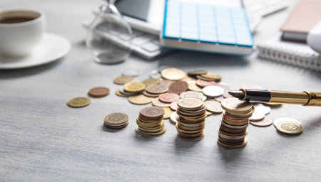 Stack of coins on the desk with a business objects.