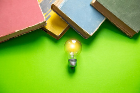 Light bulb with a book on the green background.