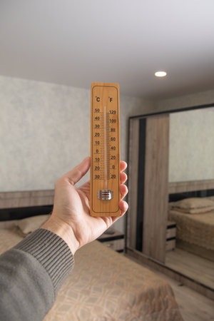 Male hand showing thermometer at room.