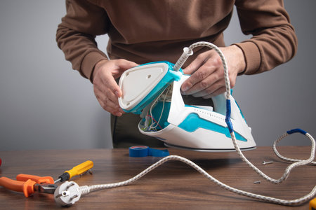 Caucasian man repairing broken iron. Iron repairの写真素材