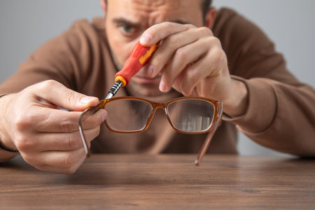Technician repairing eyeglasses with screwdriver.の写真素材