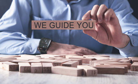 Businessman holding wooden block with text We guide you, business concept