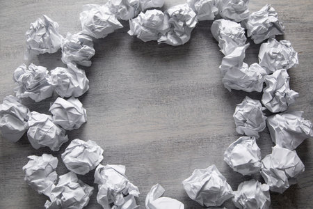 White crumpled paper balls forming a frame on grey wooden background