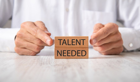 Businessman showing Talent Needed message on wooden block.