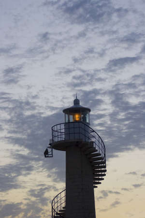 Lighting lighthouse tower from croatia after sunset in front of a cludy sky.の写真素材