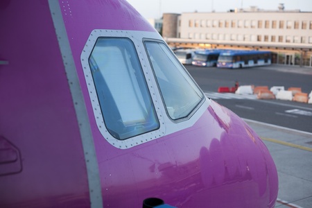 Detail of airplane nose with pilot cabin with an airport in the background.の写真素材