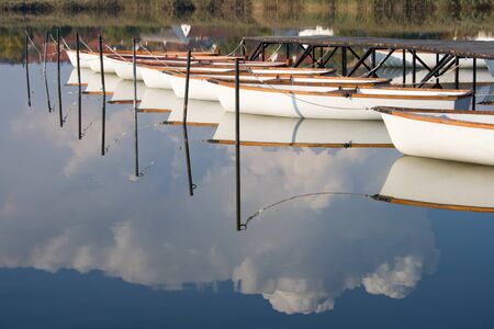 Water mirroring white boats and the cloudy sky.の写真素材