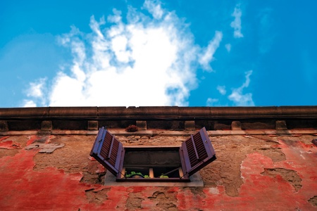 Abstract color composition with an open window on a lurid red wall and vivid blue sky の写真素材