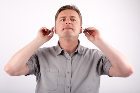 Portrait of a middle-aged man putting on his hearing aidsの写真素材