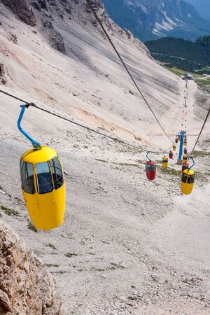 Red and yellow cable car in the Dolomite Mountains near to Cortinaの写真素材