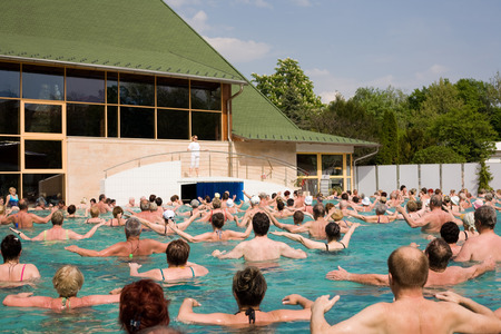 Harkany, Hungary - April 4, 2011: Lots of people doing exercises in a thermal pool following a woman trainer's instructionsのeditorial素材