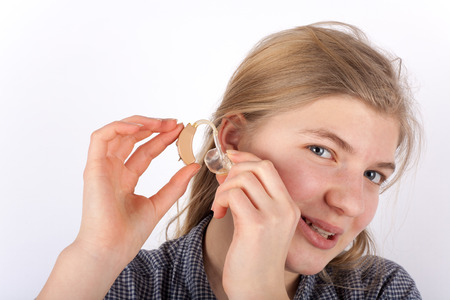Young woman shows how to insert a hearing aid into ear.
