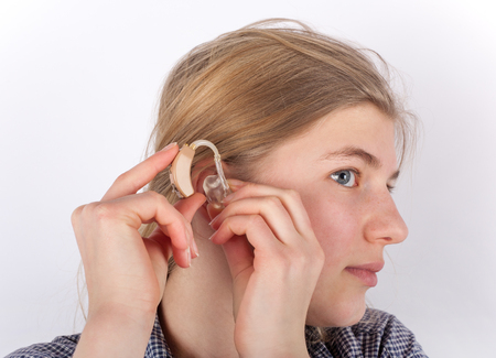 Girl inserting her hearing aid.